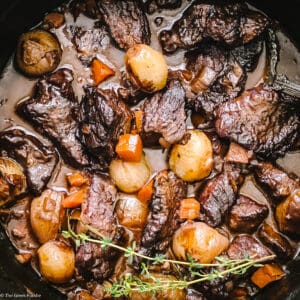 A white pot with Stifado-red wine beef stew on a white table.