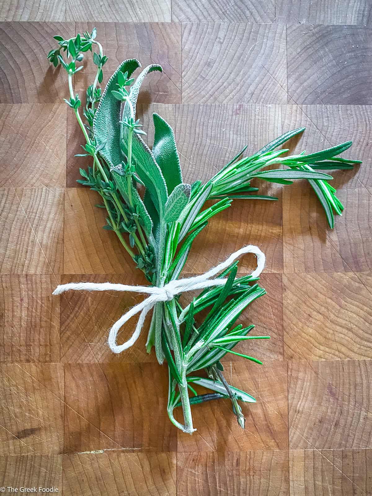 Fresh herbs tied together on a cutting board.