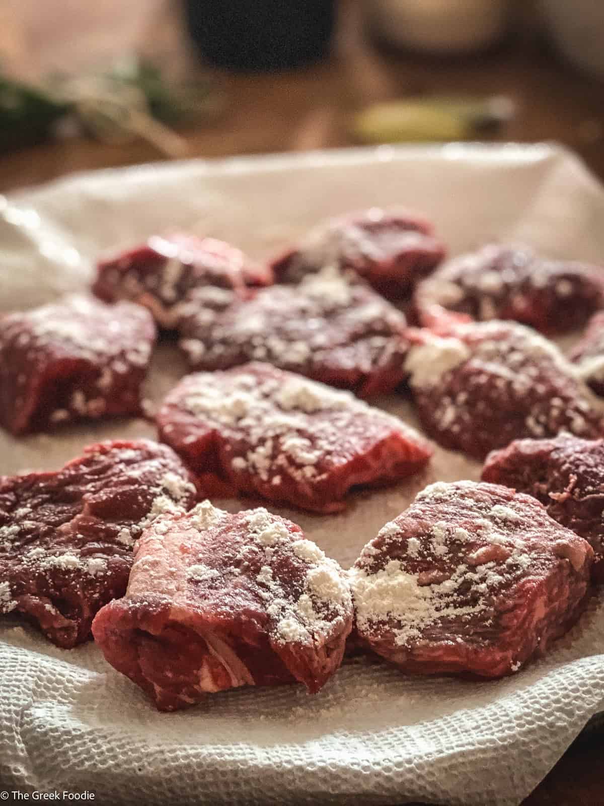 Pieces of beef dusted with flour on paper towel.