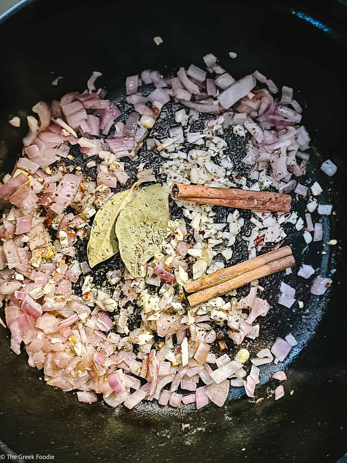 Diced onions , cinnamon sticks, bay leaves in a pot.