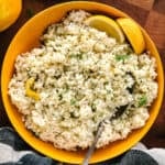 A yellow plate with greek lemon rice and a spoon.