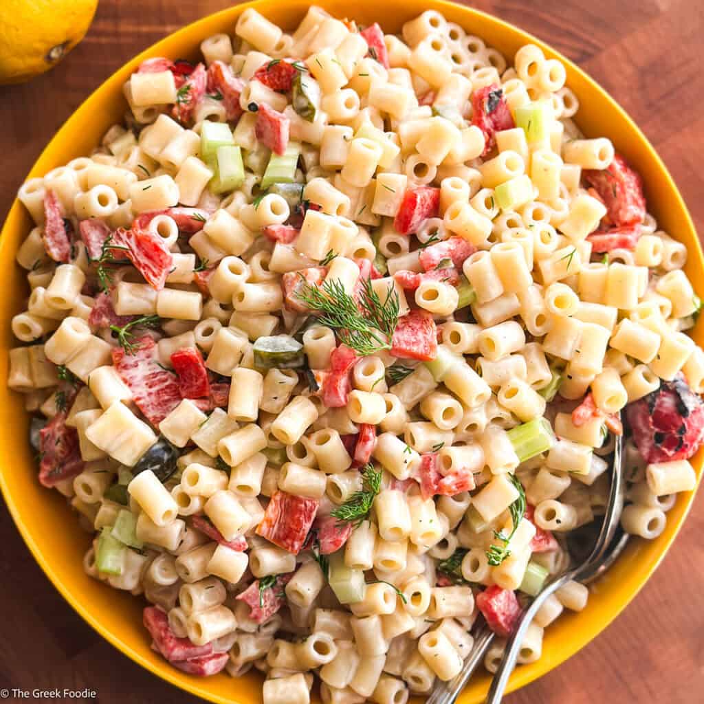 A plate with Greek pasta salad on a wooden table.