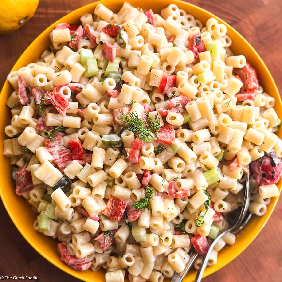 A plate with Greek pasta salad on a wooden table.