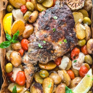 A leg of lamb with potatoes, tomatoes, olives and herbs in parchment paper.