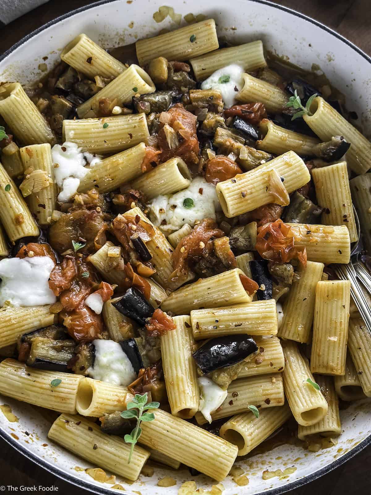 Diced roasted eggplants and roasted tomatoes cooking in a white pot.