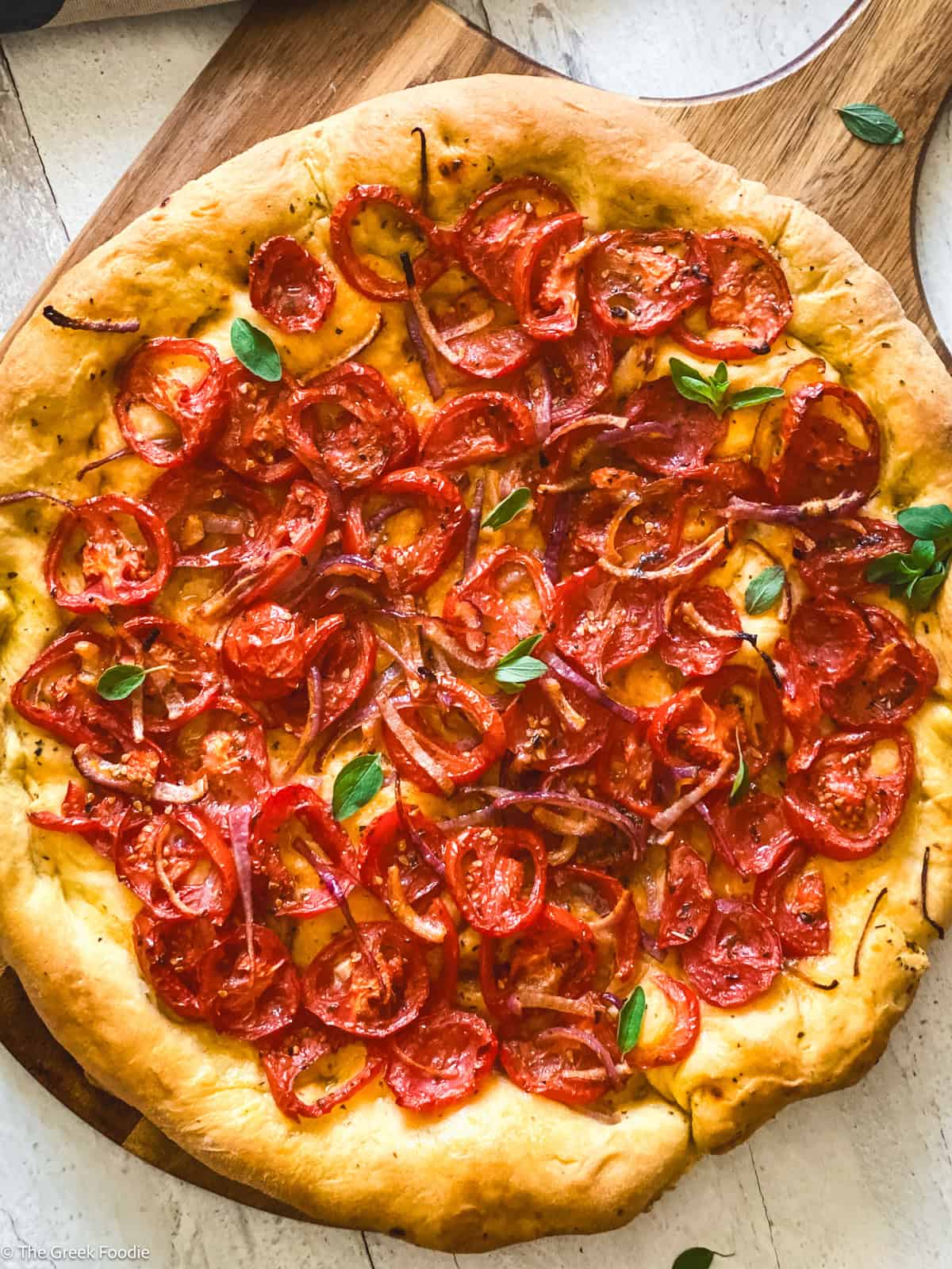 A Ladenia olive oil pie, Greek pizza on a wooden board.