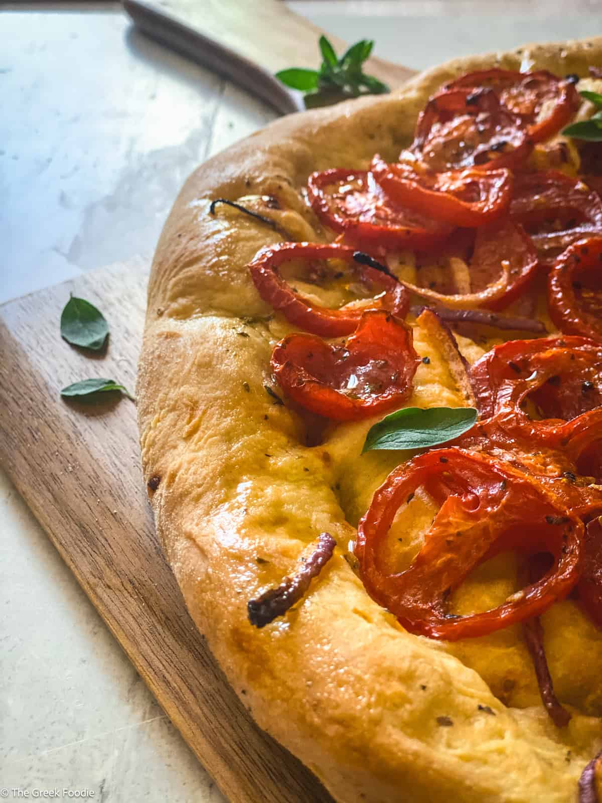 A Ladenia olive oil pie, Greek pizza on a wooden board.