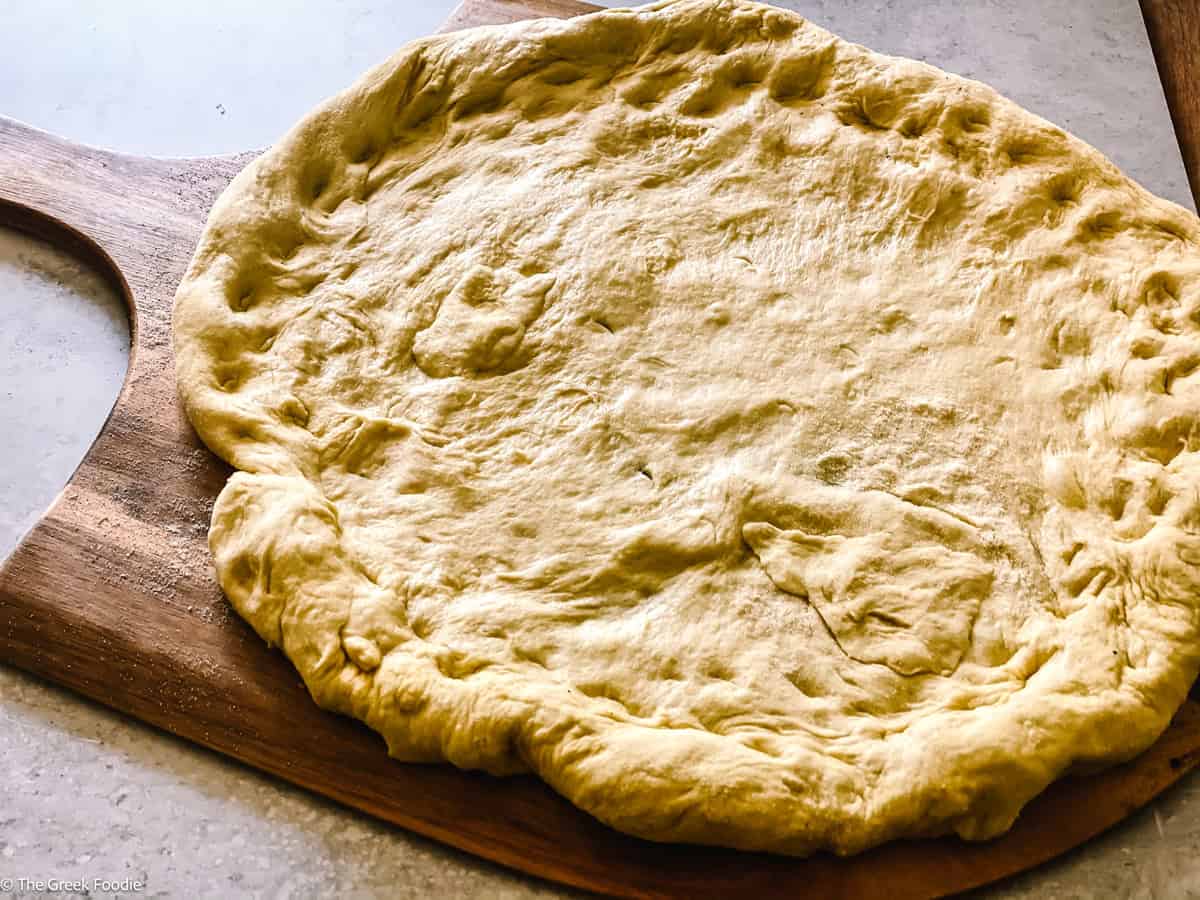 Pizza dough on a wooden board.