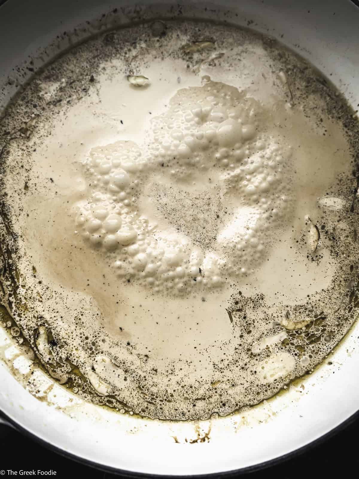 A white sauce cooking in a skillet.