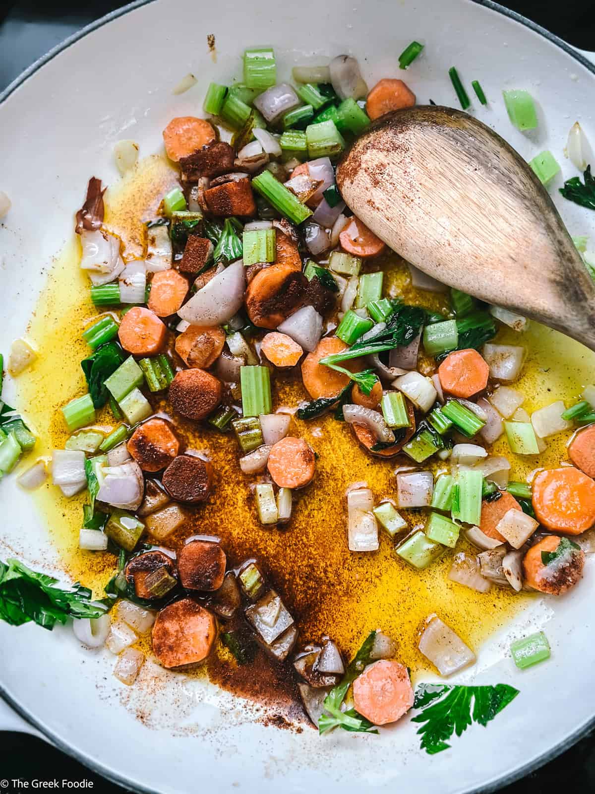 Vegetables and seasoning in a pot with a wooden spoon.