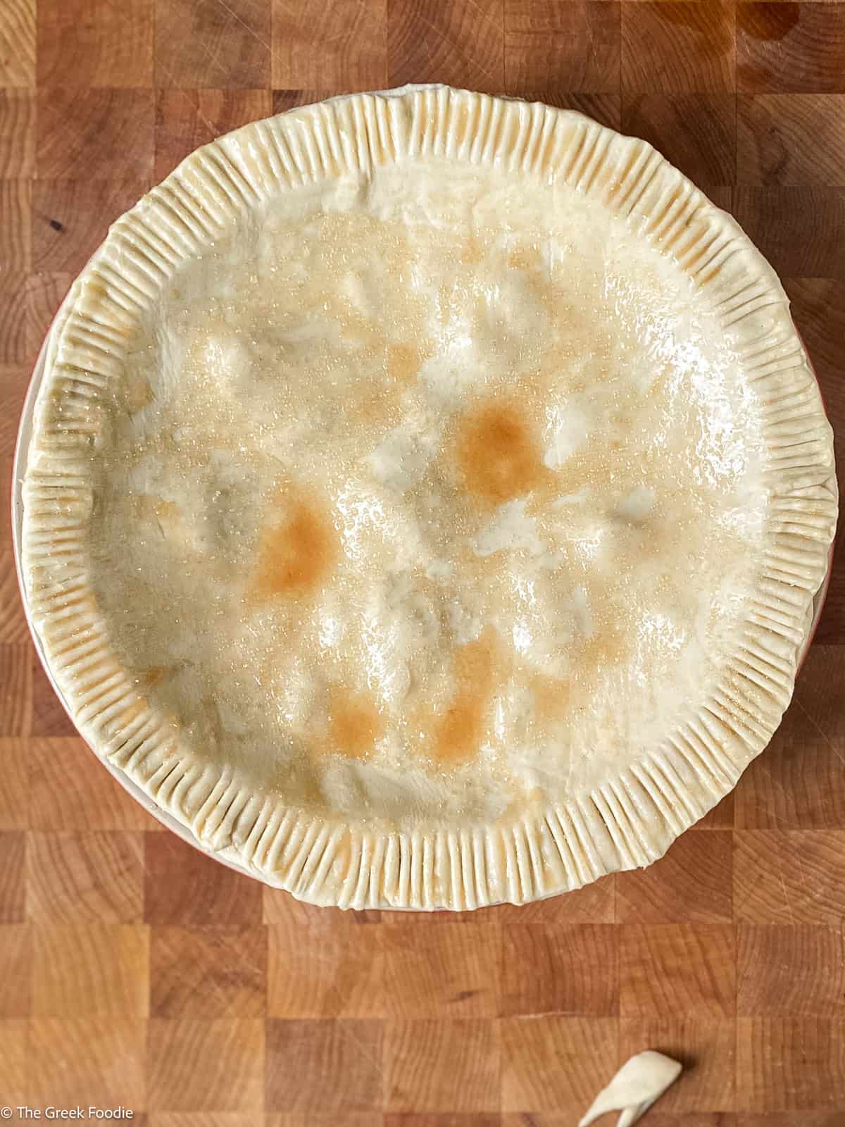 An apple pie ready for the oven on a table.