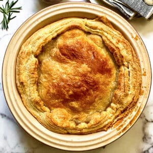 An apple pie in a round tart pan, a canister with sauce, naplins and serving utensils.
