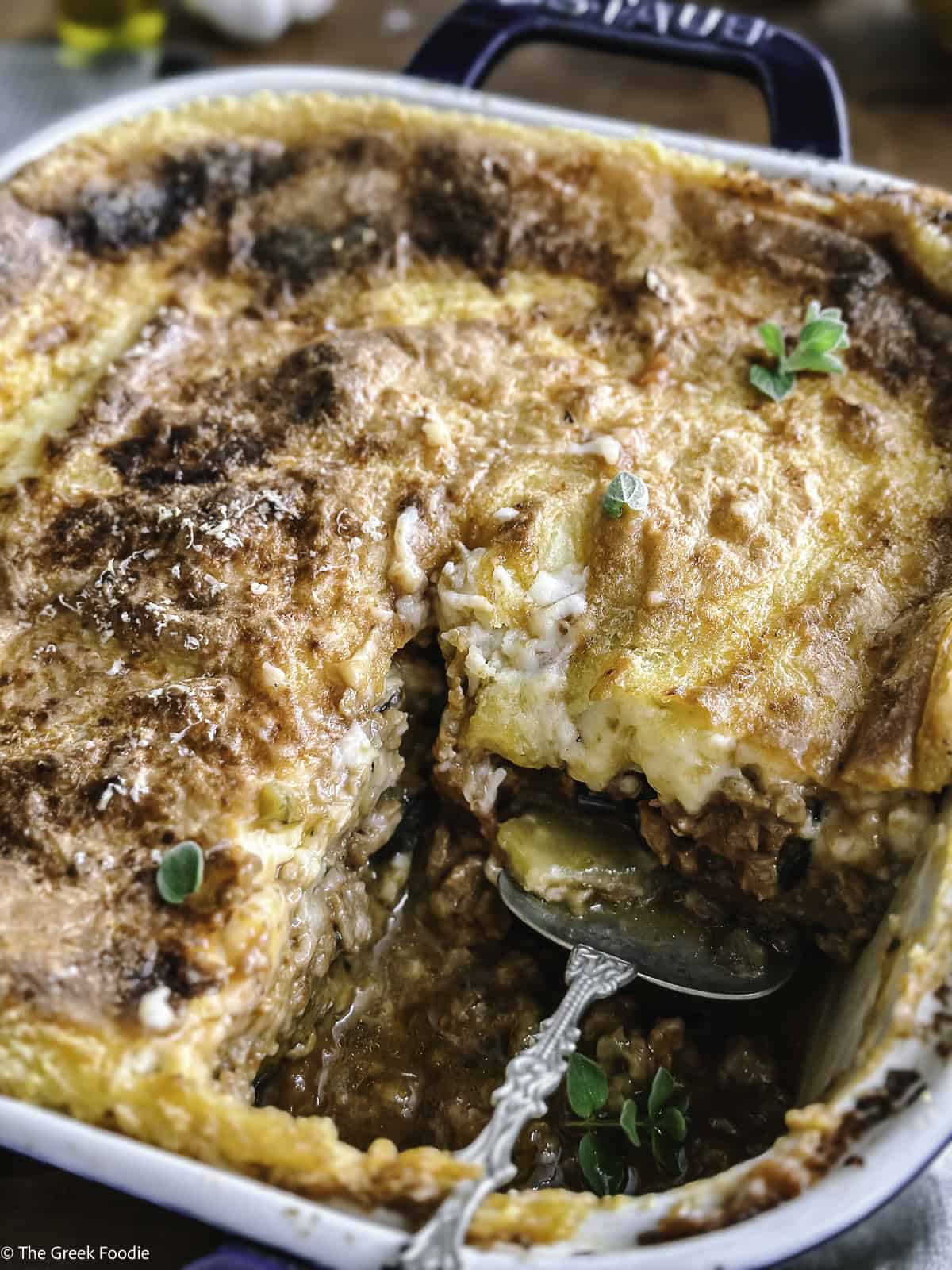 A vegetarian moussaka with a piece taken out and a serving spoon.