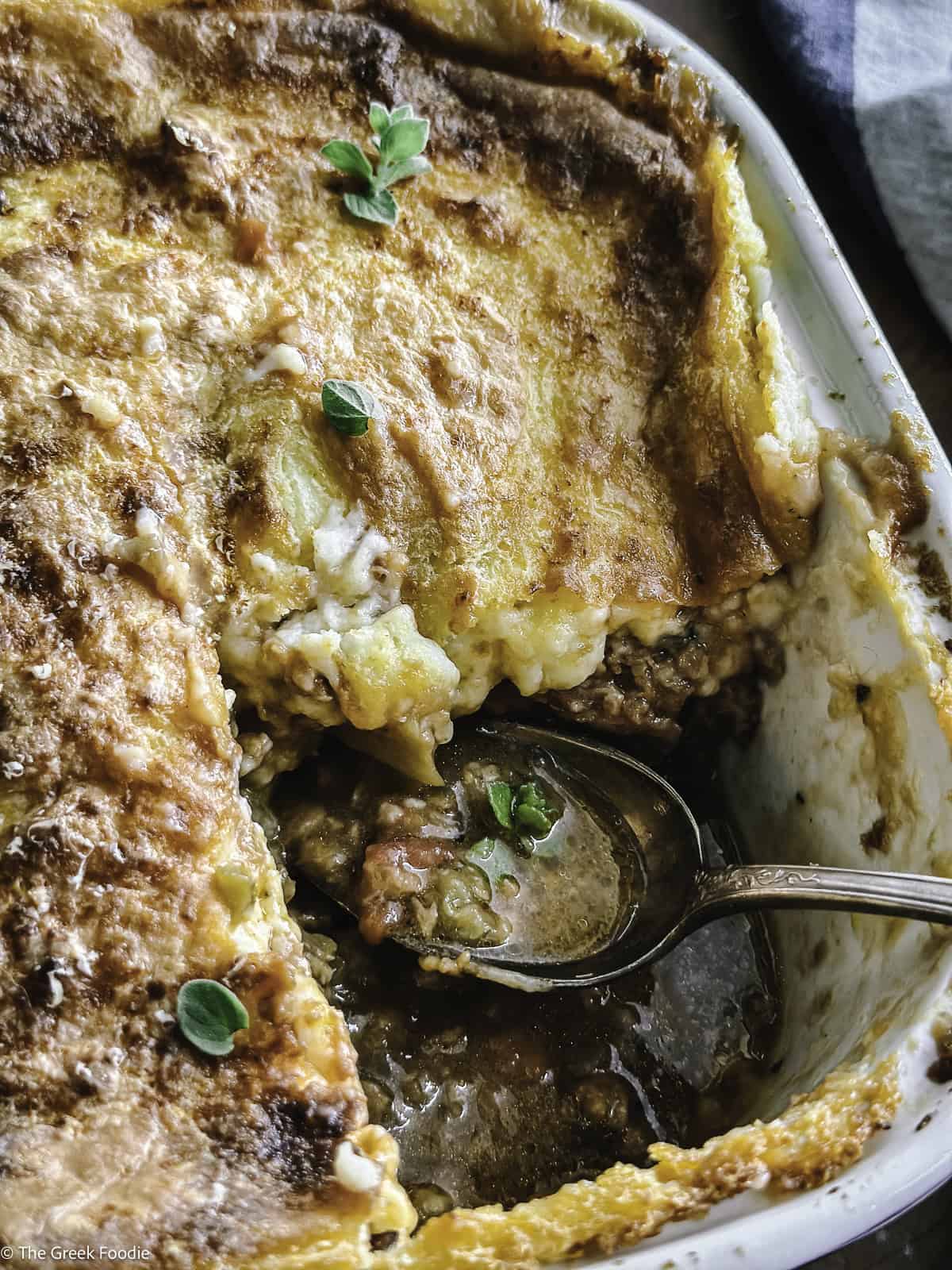A vegetarian moussaka with a piece taken out and a serving spoon.