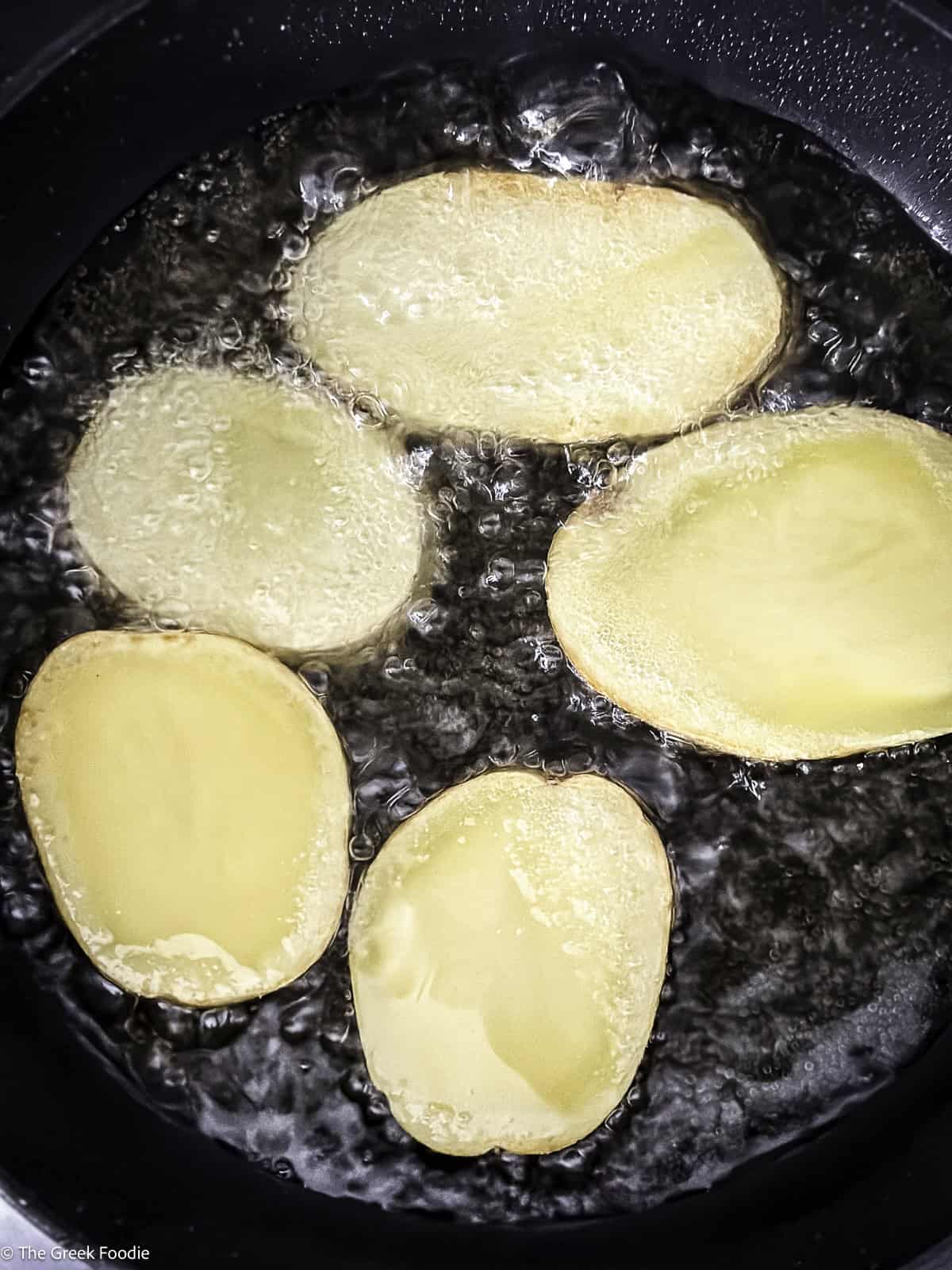 Four potato slices frying.