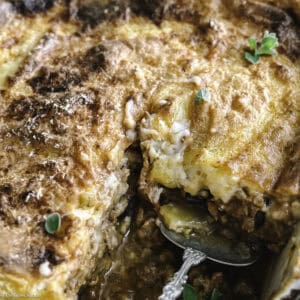 A vegetarian moussaka with a piece taken out and a serving spoon.