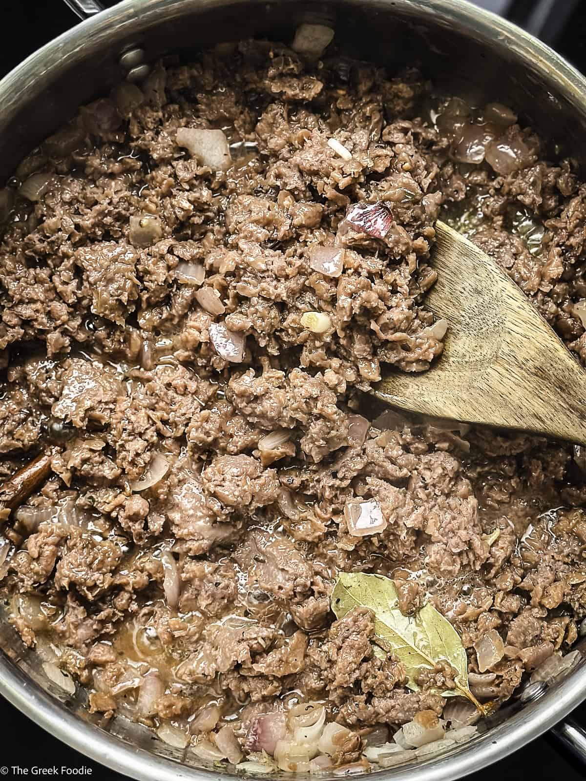 Plant based meat in a skillet with a wooden spoon.
