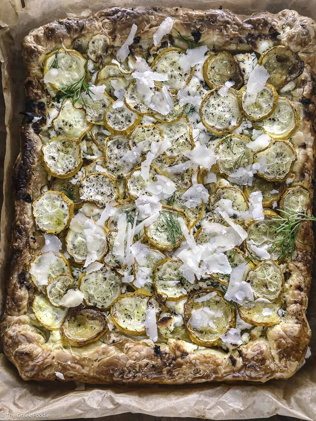 A yellow zucchini puff pastry tart on parchment paper.