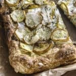 A piece of zucchini puff pastry tart on parchment paper.