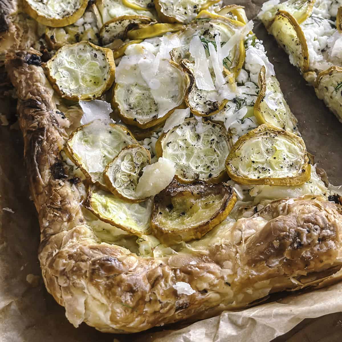 A piece of zucchini puff pastry tart on parchment paper.