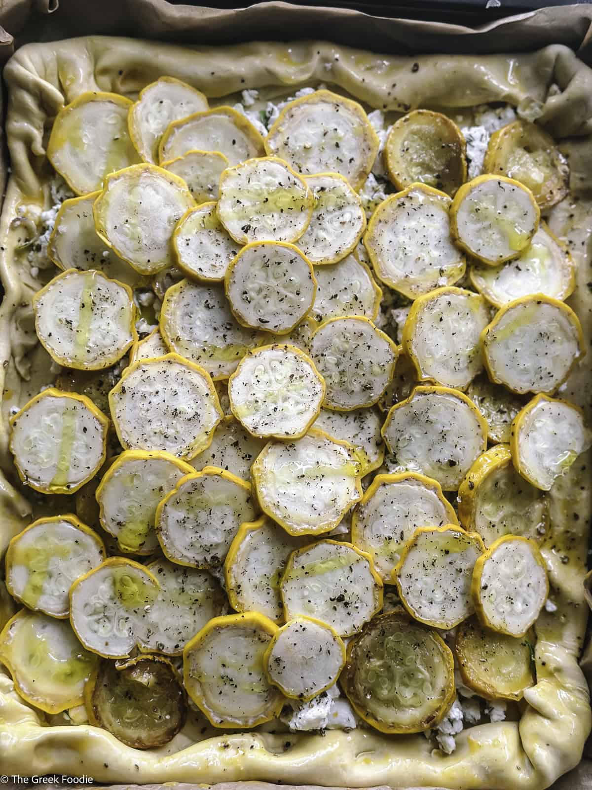 Sliced yellow zucchini over cheese and puff pastry.