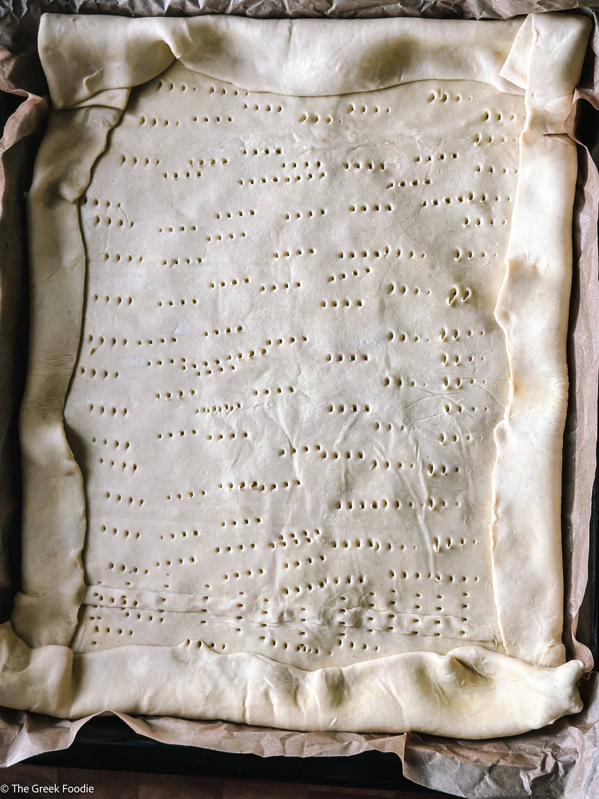 Puff pastry on parchment paper on a baking sheet.