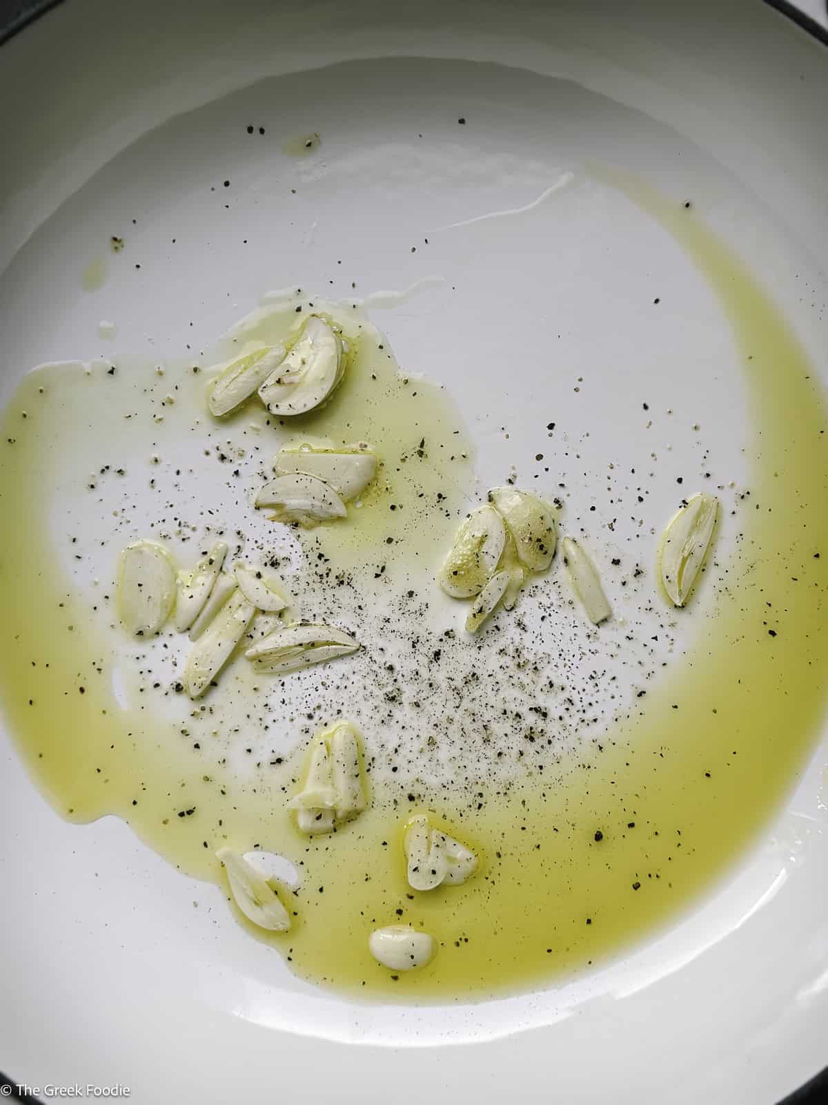 Sliced garlic and olive oil in a skillet.