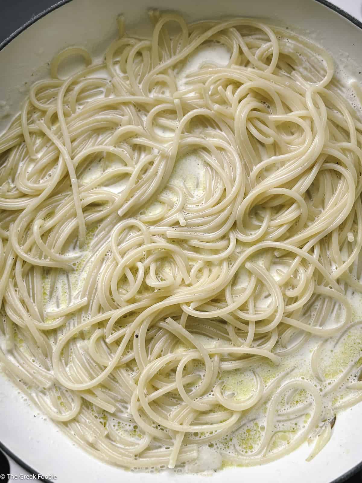 Spaghetti, cream, lemon zest and pepper in a skillet.