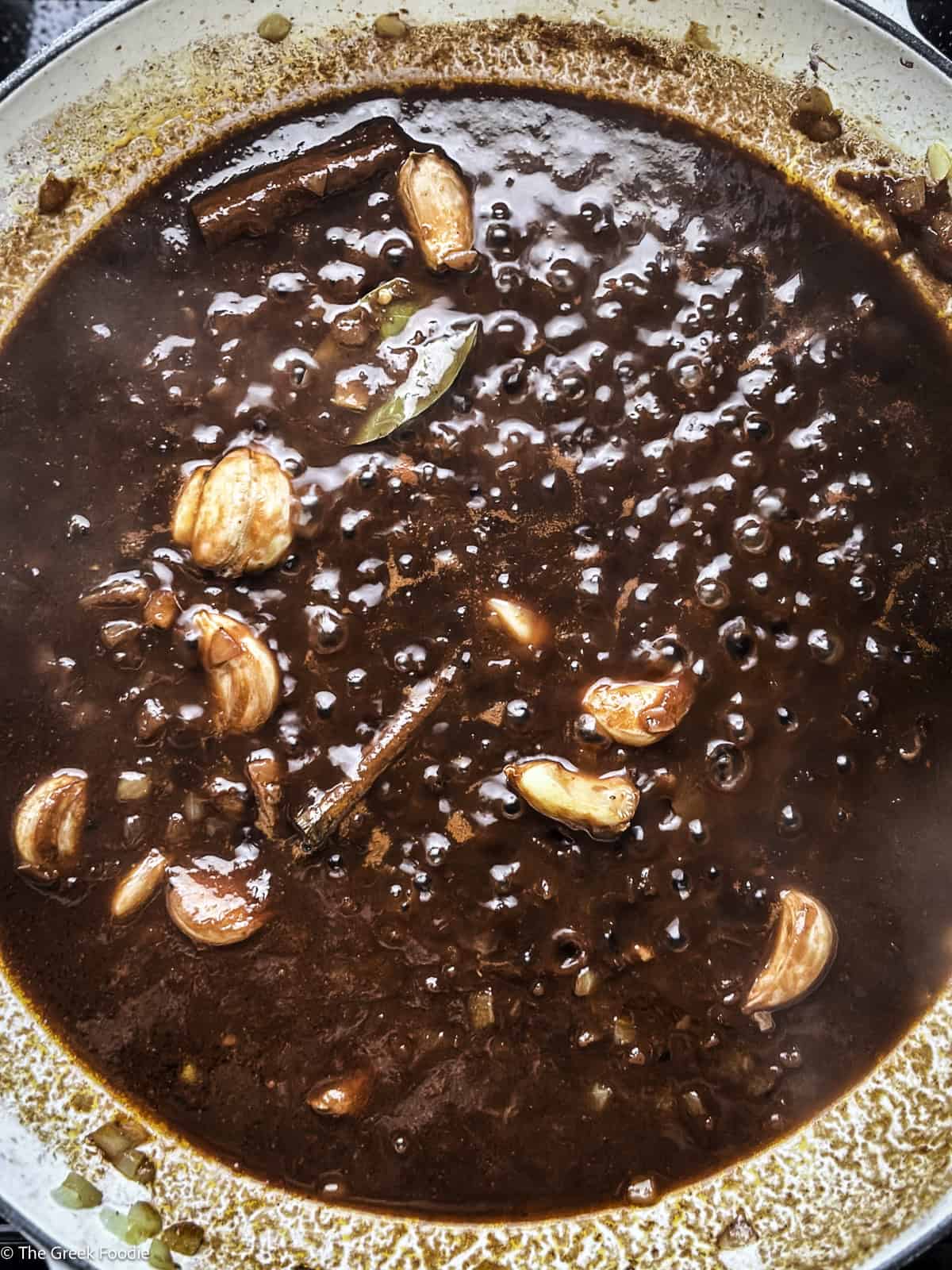 Wine sauce cooking in a white skillet.