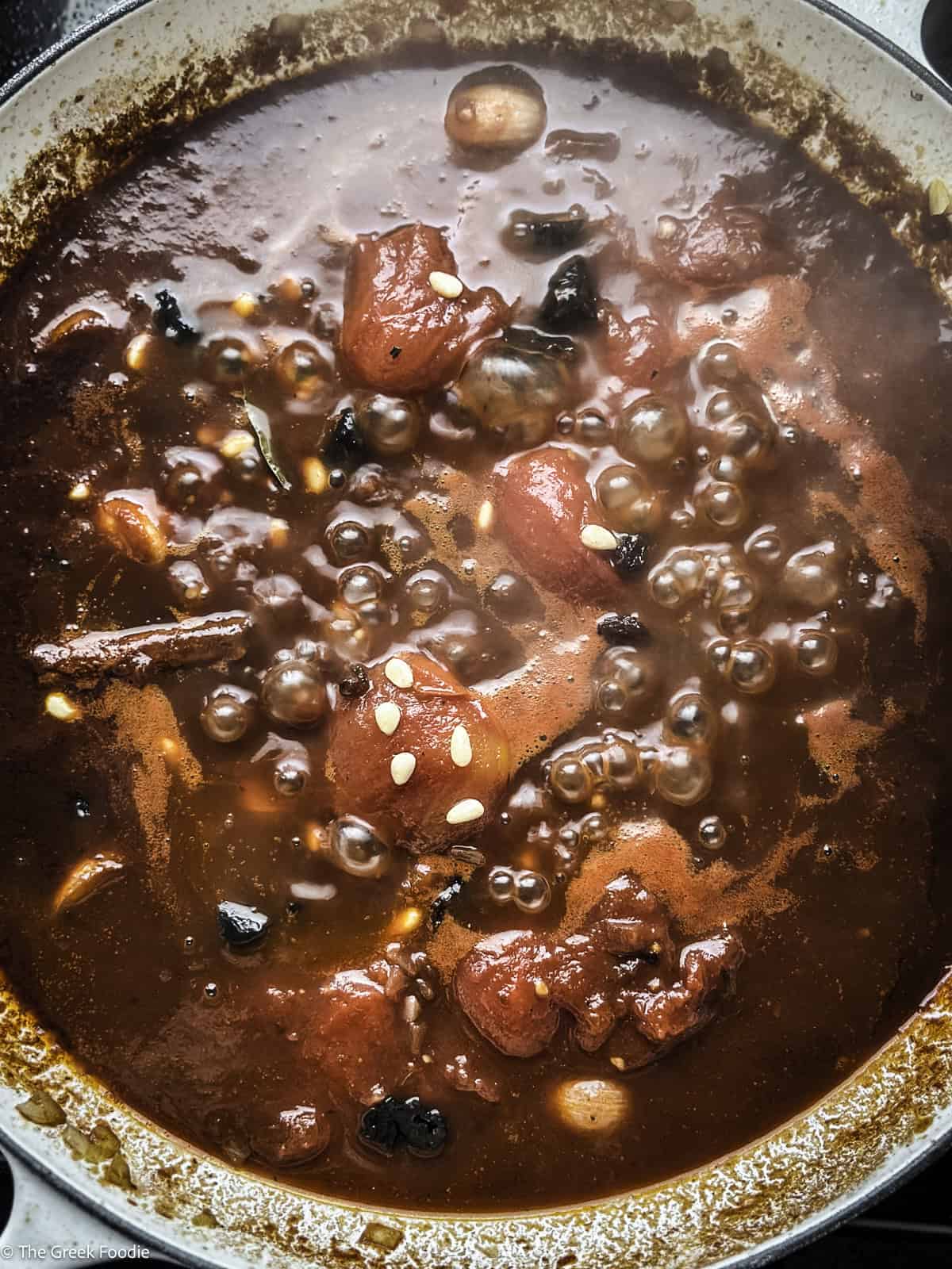 Wine sauce cooking in a white skillet.