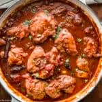 A white skillet with Greek chicken stew.