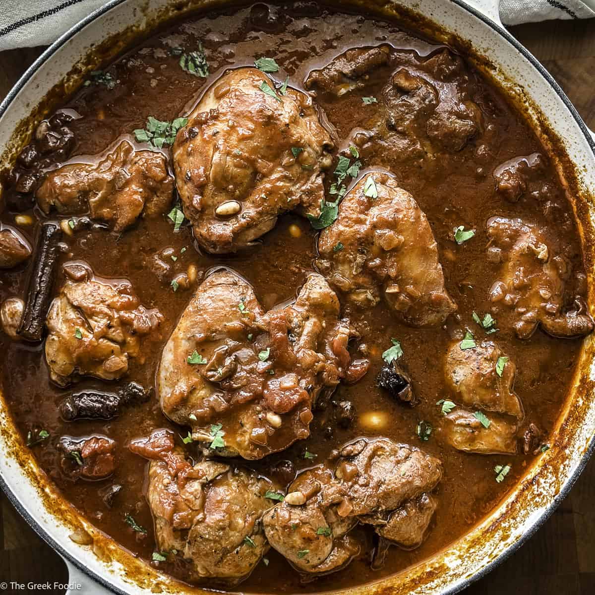 A white skillet with Greek chicken stew.