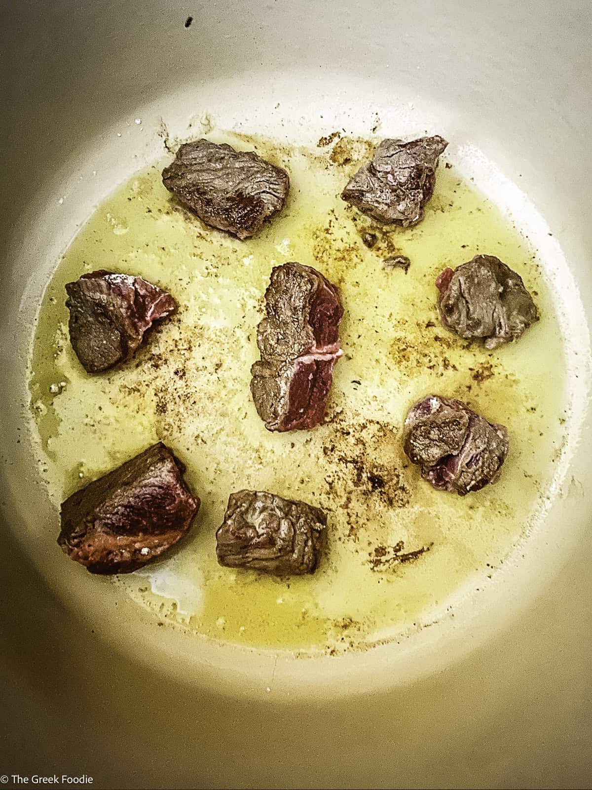 Pieces of stew meat browning in a pot.
