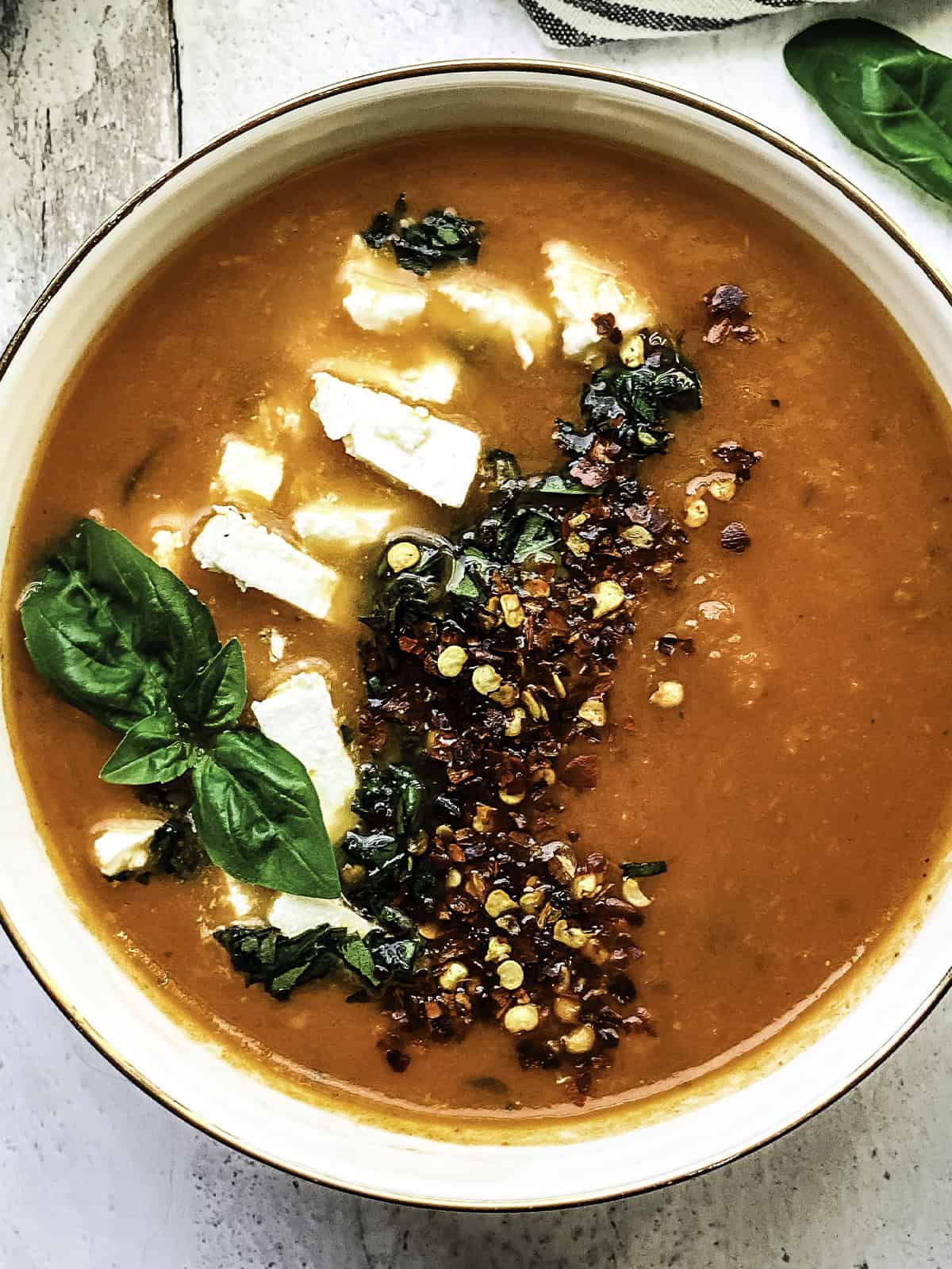 A bowl with Greek tomato soup with feta and basil.