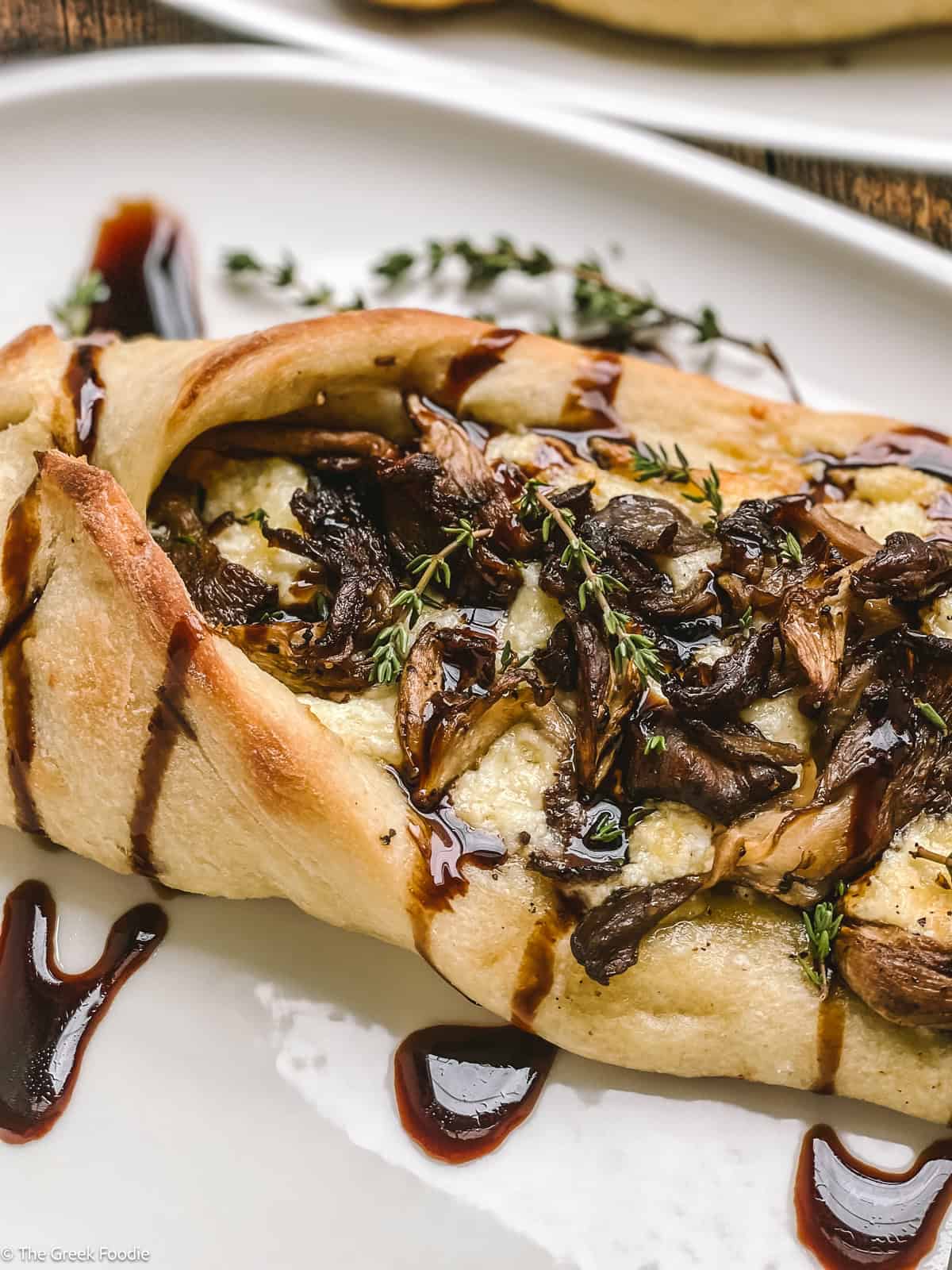 Peinirli with mushrooms and drizzled balsamic cream on a plate.