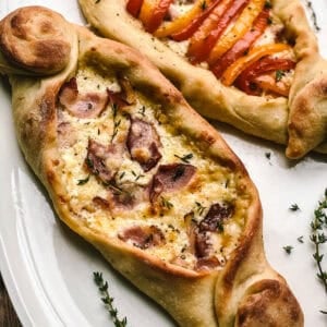 Two peinirli, Greek pizza boats on a platter.