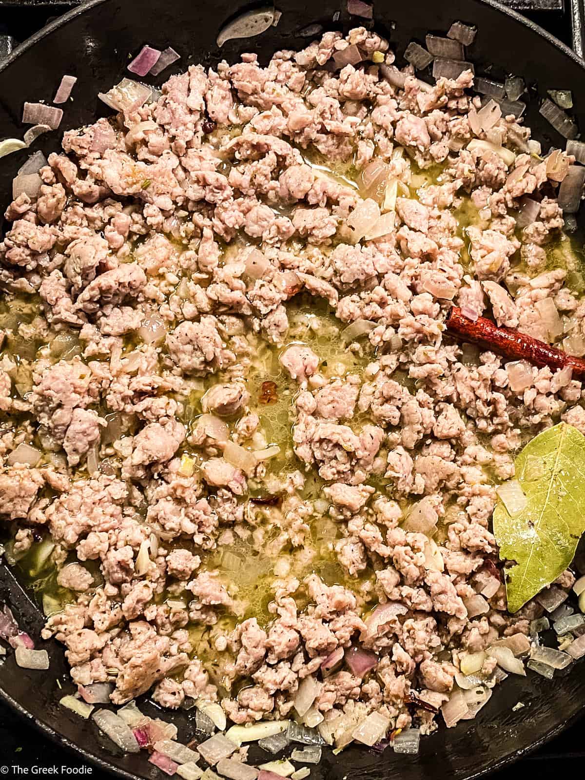 Ground sausage and onions cooking in a skillet.