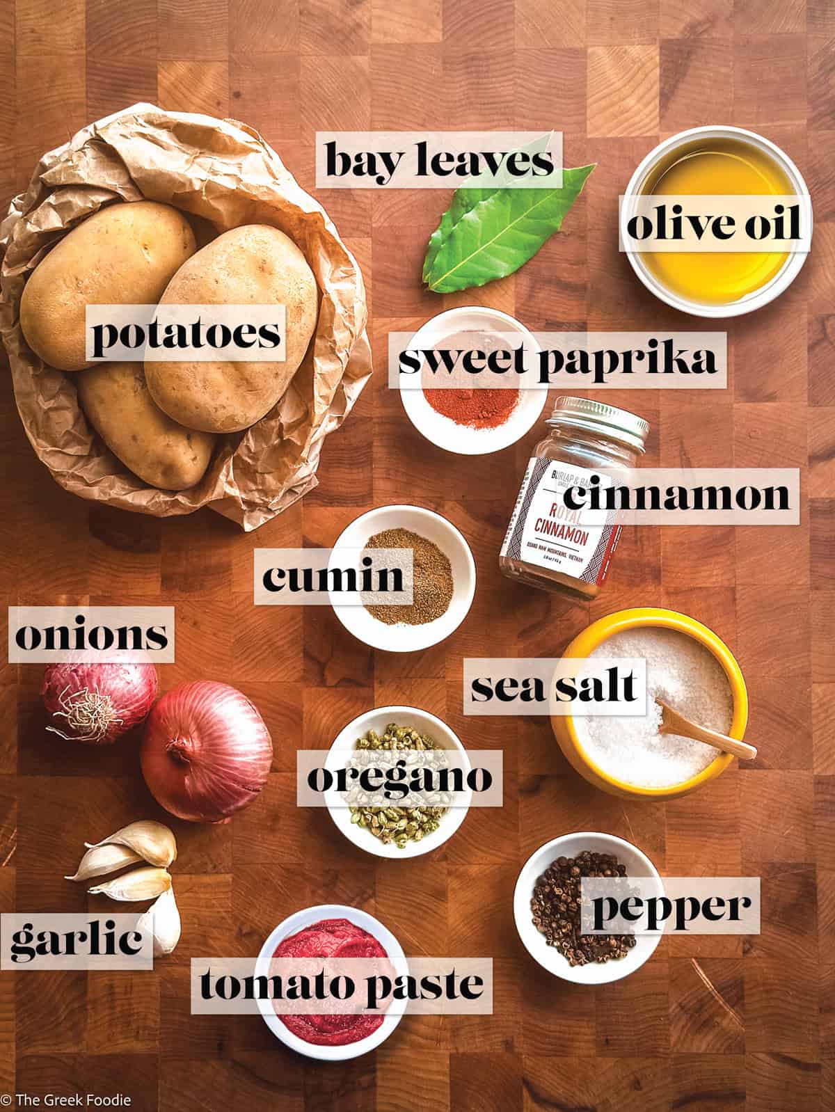 Ingredients to make Greek potato stew on a wooden surface.