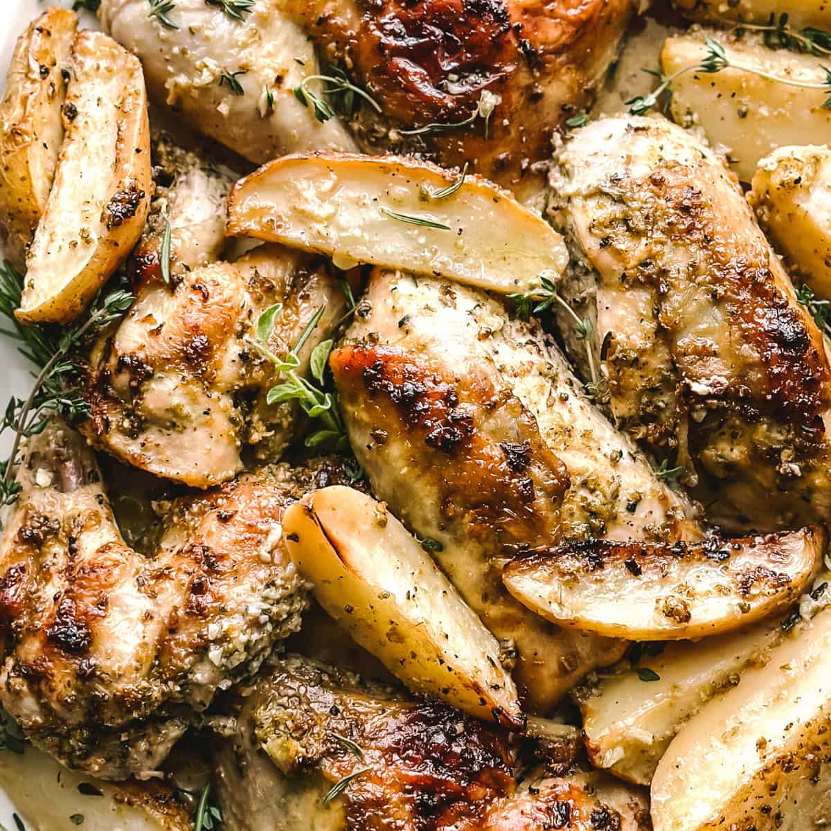 A platter with Greek lemon chicken cut in pieces and roasted potatoes.