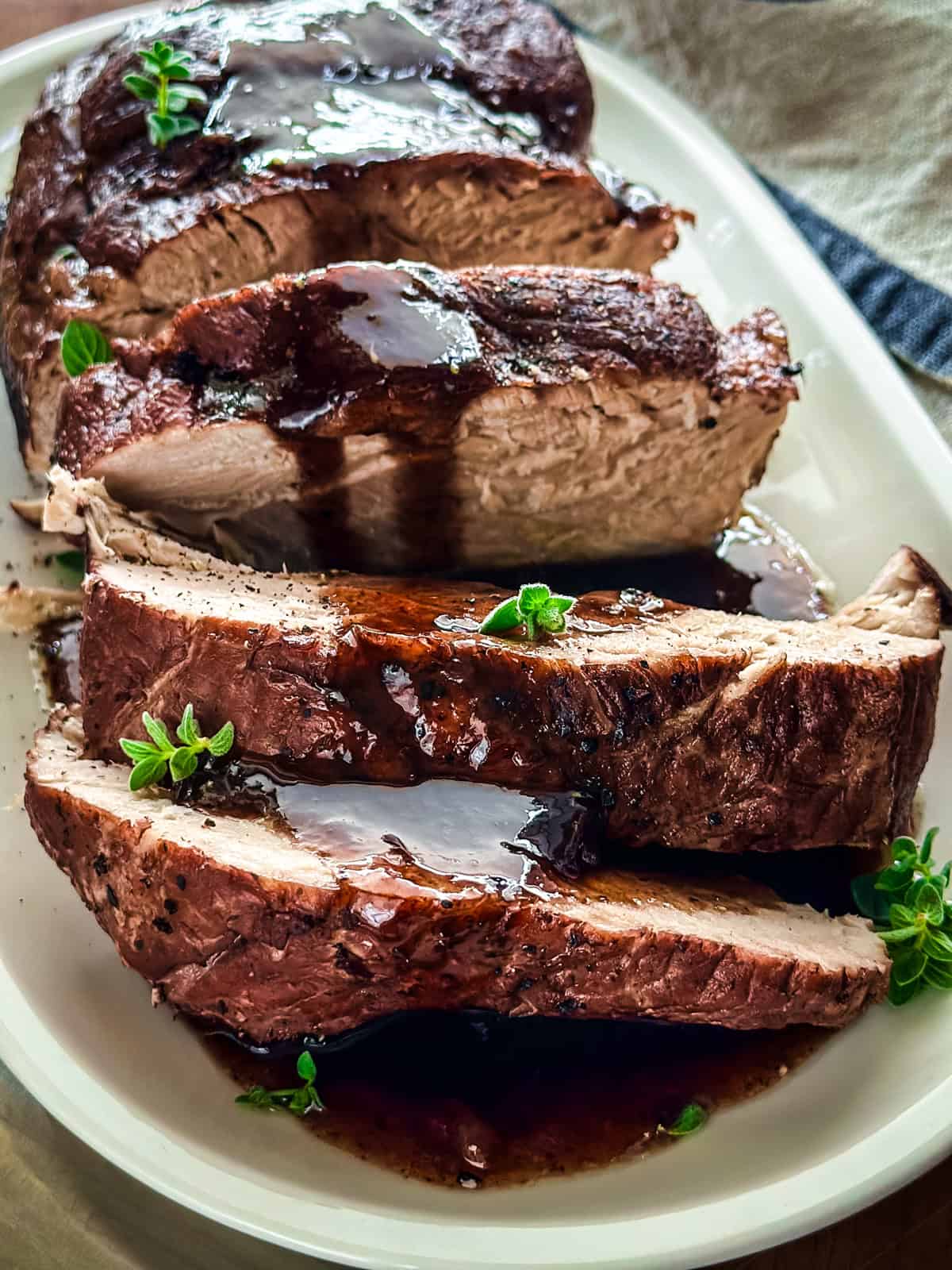 A pork shoulder sliced with wine sauce on a platter.