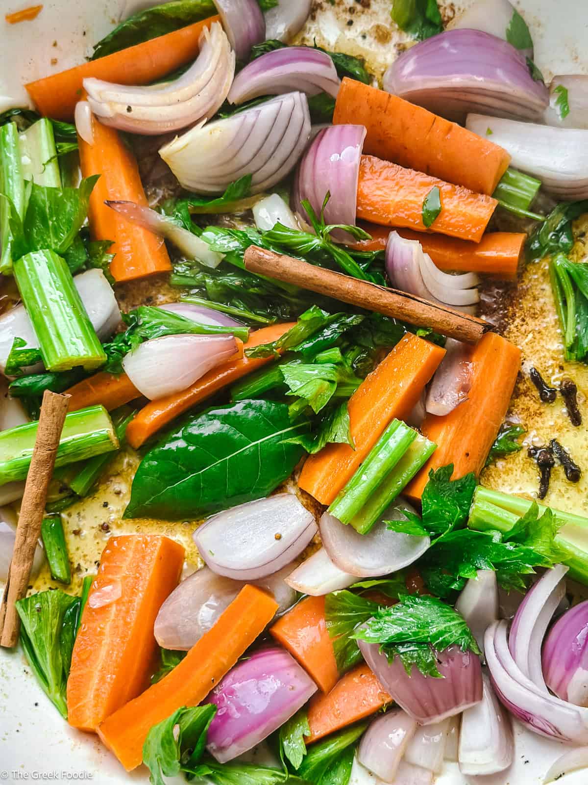Onion, celery and carrots softening in olive oil with bay leaf, cinnamon and cloves