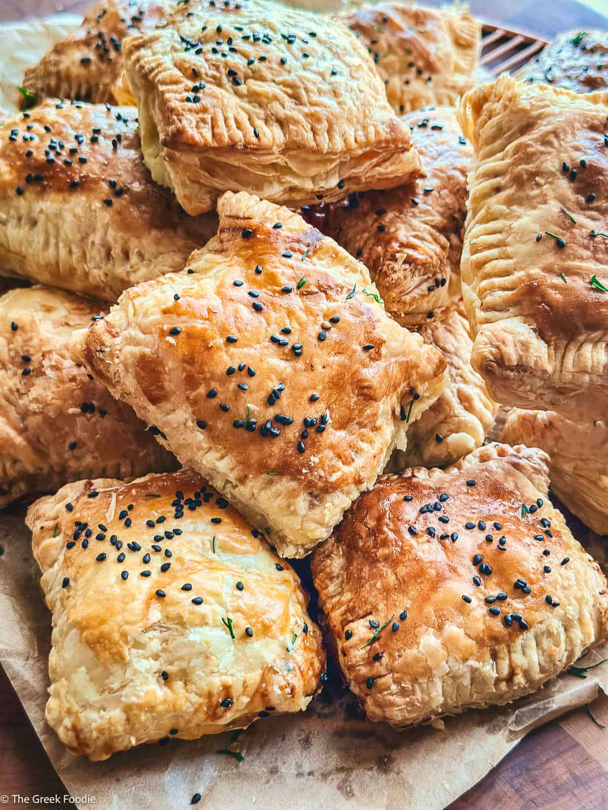 A pile of cheese puff pastries on parchment paper.