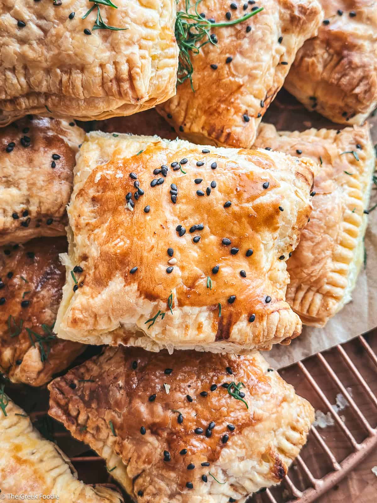 A pile of cheese puff pastries on parchment paper.