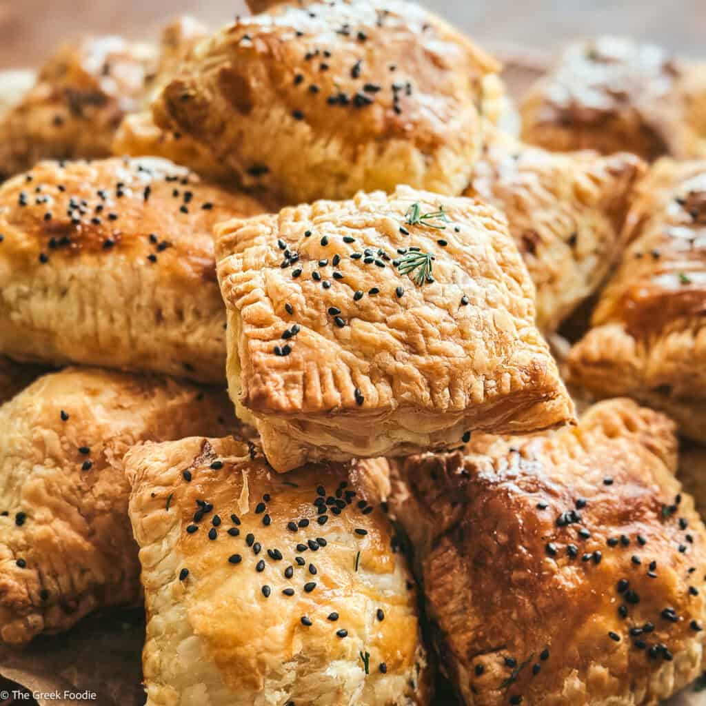 A pile of cheese puff pastries on parchment paper.