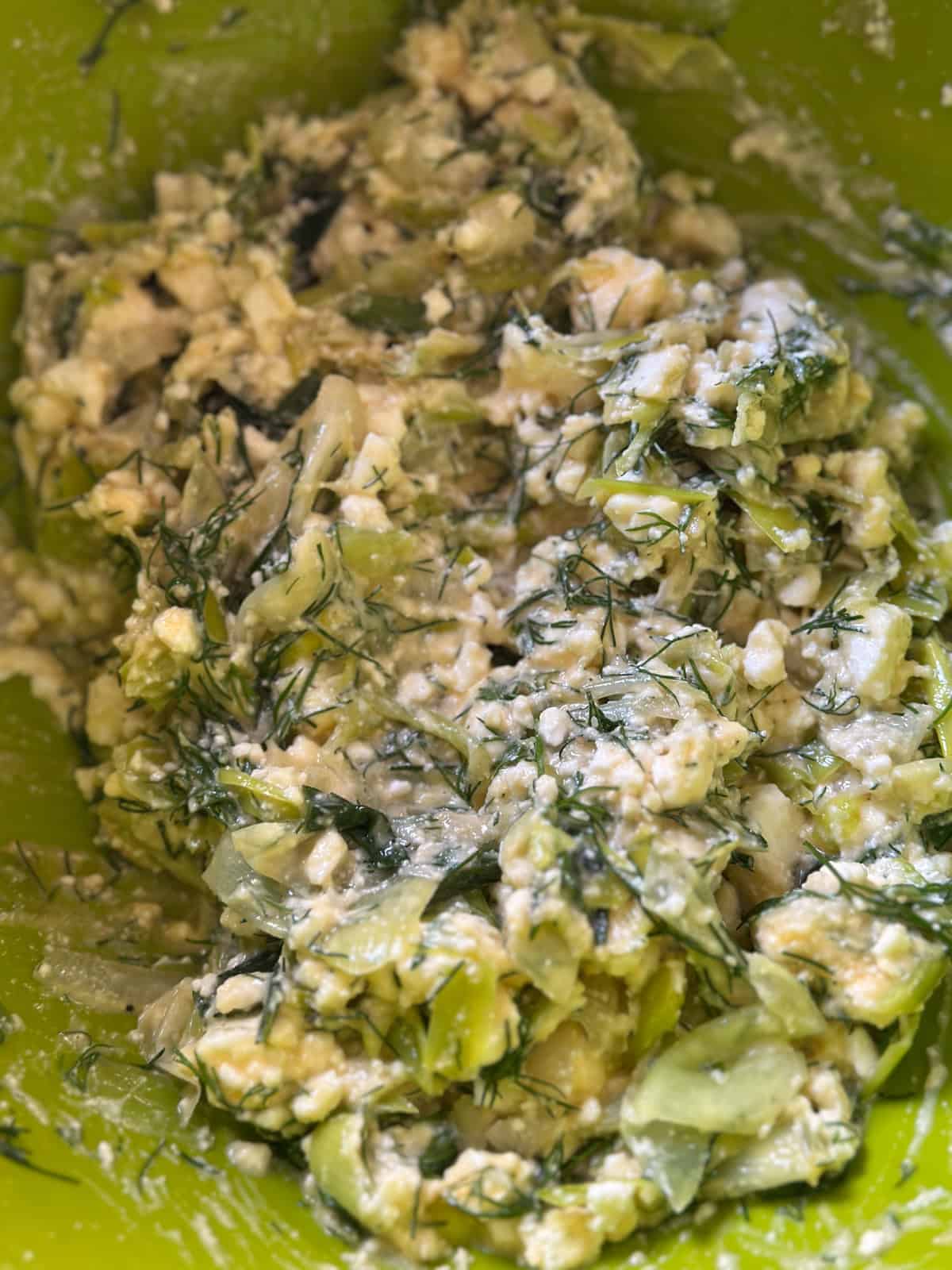 Leeks, feta and onions mixed in a bowl.