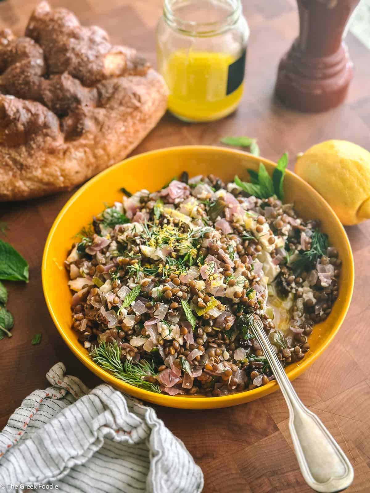 Greek lentil salad with feta in a bowl with a spoon, on a table.