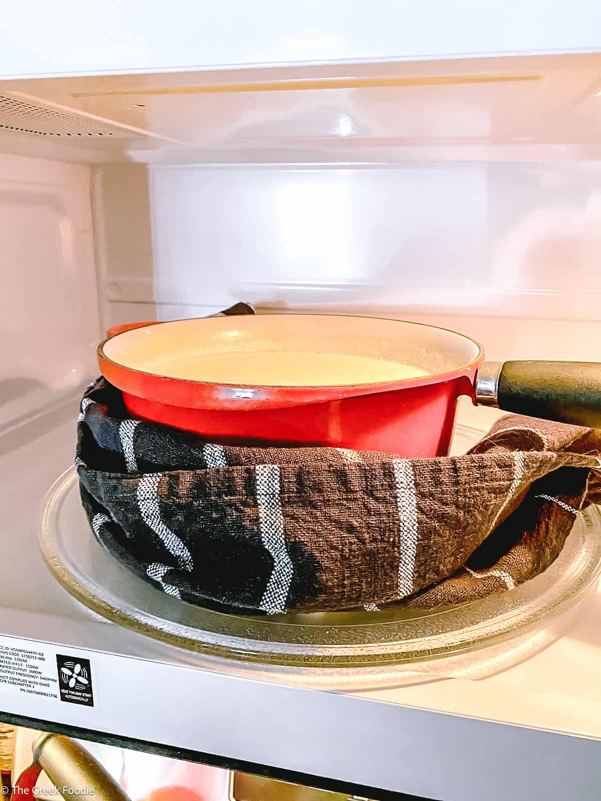 A saucepan in a microwave with the light on.