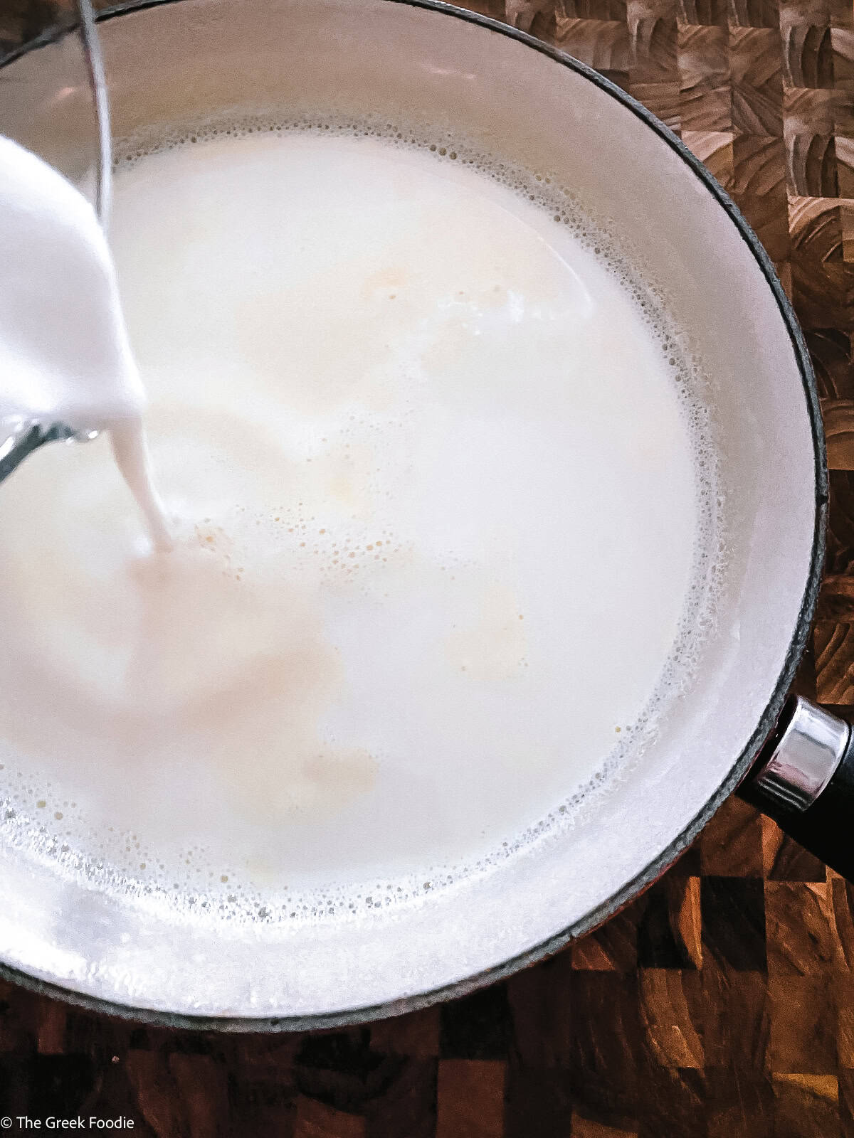 Pouring milk in a saucepan full of milk.
