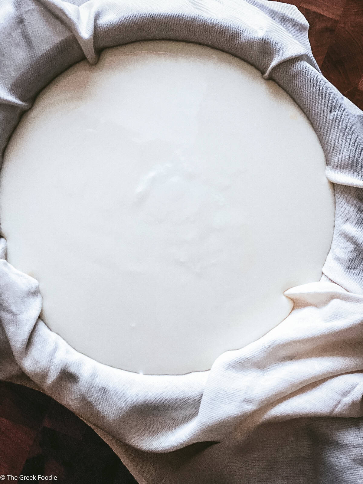 Yogurt straining through a cheese cloth in a big bowl.