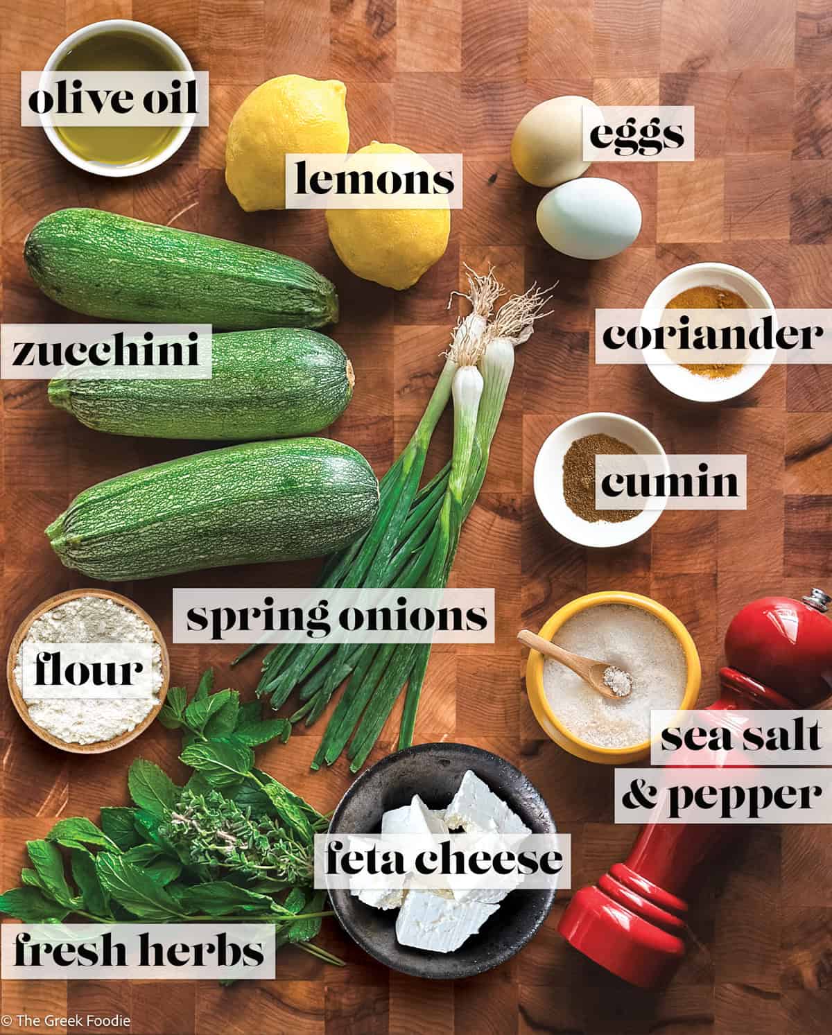 Zucchini, lemons spices, herbs, feta for making zucchini fritters.